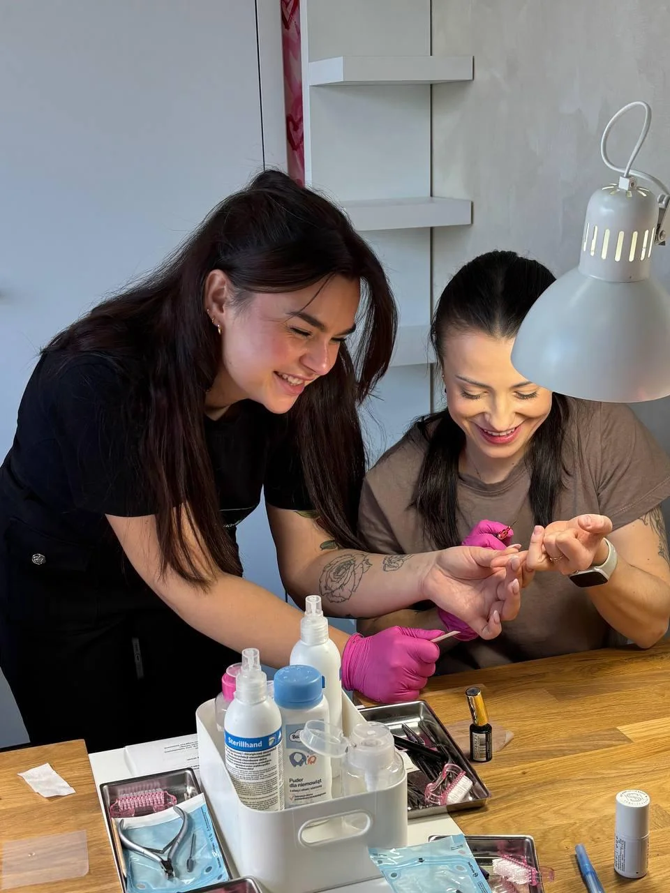 Instruktorka Akademii Przyjaciółek wspiera kursantkę podczas ćwiczeń manicure hybrydowego